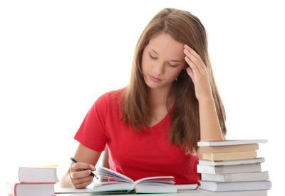 Teenage girl studying at the desk being tired, isolated on white